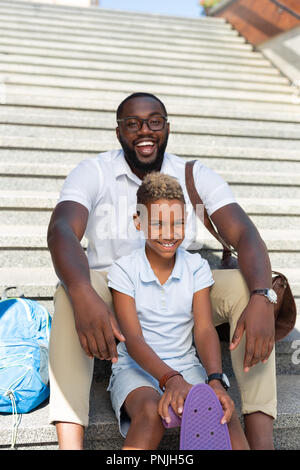 Delighted nice father and son sitting on the stairs Stock Photo