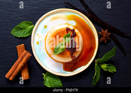Food Dessert concept homemade vanilla Caramel custard or panna cotta with vanilla beans and spices on black stone background