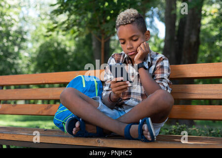 Sad nice boy looking at his smartphone screen Stock Photo