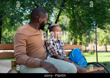 Delighted nice father and son sitting on the bench Stock Photo
