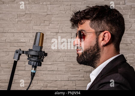 singer with sunglasses in front of a microphone in music studio Stock Photo