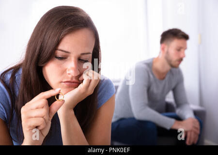 Close-up Of A Upset Young Woman Holding Golden Wedding Ring Stock Photo