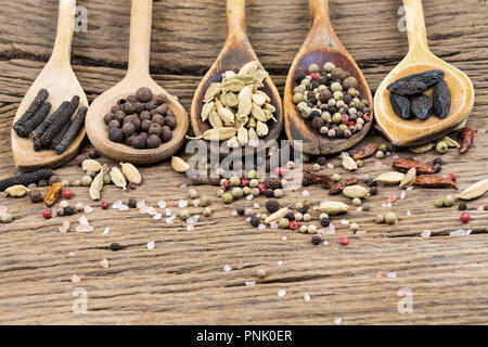 Closeup of five wooden cooking spoons in a row with various exotic spices on a rustic wooden background with more spices and copy space Stock Photo