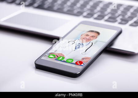 Mobile Phone Screen Showing Video Conference Of A Happy Male Doctor Stock Photo
