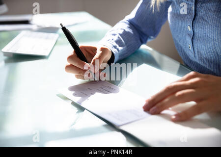Close-up Of A Businesswoman's Hand Signing Cheque Stock Photo