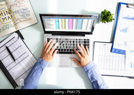 Elevated View Of Businesswoman's Hand Analyzing Data On Laptop Over Desk Stock Photo