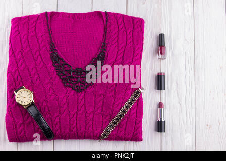 Purple sweater with jewellery, accessories and cosmetics. Female outfit on wooden background Stock Photo