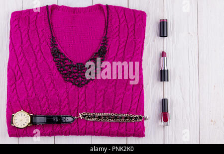 Purple sweater with jewellery, accessories and cosmetics. Female outfit on wooden background Stock Photo