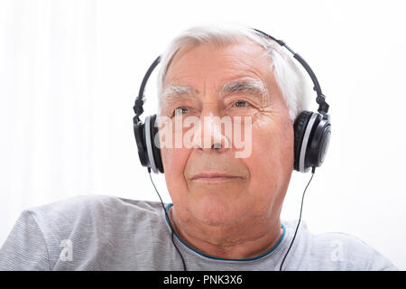 Portrait Of A Senior Man Listening To Music On Headphone At Home Stock Photo