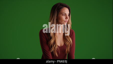 Pensive Caucasian millennial female looking offscreen on green screen Stock Photo