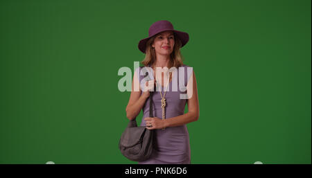 Middle aged woman in fancy clothes standing with purse on green screen Stock Photo