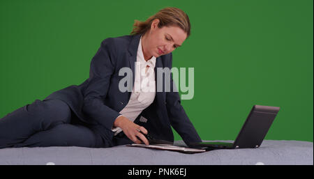 Professional businesswoman on bed with laptop working on green screen Stock Photo
