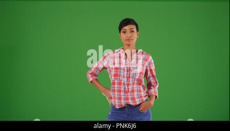 Young black woman in flannel shirt posing confidently on green screen Stock Photo