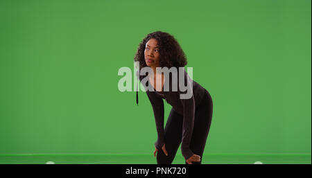 Young black woman runner taking break during workout on green screen Stock Photo