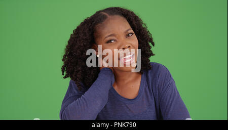 Black female with neck pain rubbing neck looking at camera on green screen Stock Photo