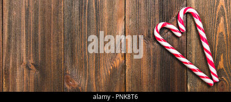 Christmas candy canes in the shape of a heart on a brown wooden table. Copy space Stock Photo