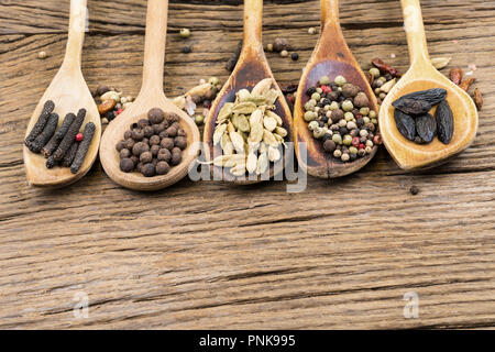 Closeup of five wooden cooking spoons in a row with various exotic spices on a rustic wooden background with more spices and copy space Stock Photo