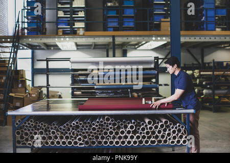 Male cutting fabric in a manufacturing warehouse Stock Photo