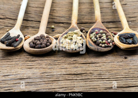 Closeup of five wooden cooking spoons in a row with various exotic spices on a rustic wooden background with copy space Stock Photo