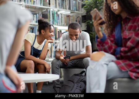 High school students looking at smartphone in a library Stock Photo