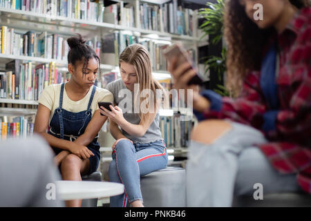 High school students looking at smartphone in a library Stock Photo