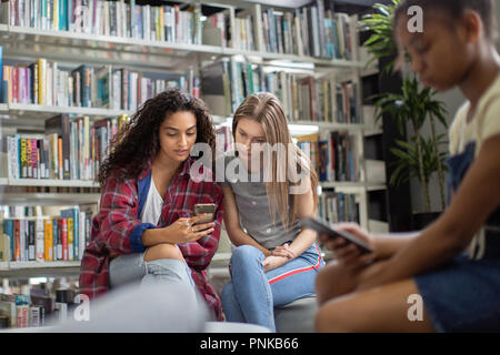 High school students looking at smartphone in a library Stock Photo