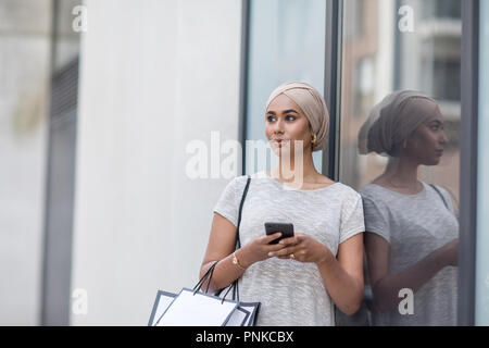 Muslim woman using a smartphone on a shopping trip Stock Photo
