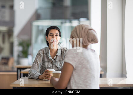 Female Muslim co-workers having coffee together Stock Photo