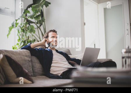 Adult male working from home in living room Stock Photo