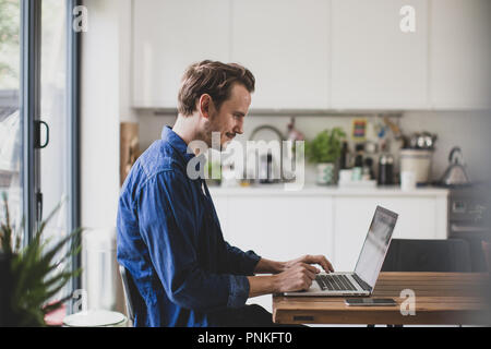 Adult male working from home in kitchen Stock Photo