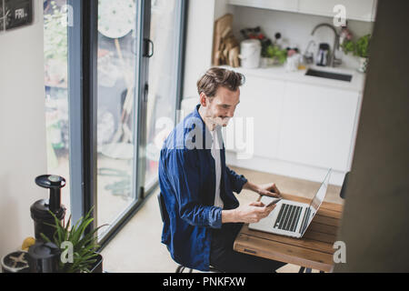 High angle shot of adult male working from home in kitchen Stock Photo