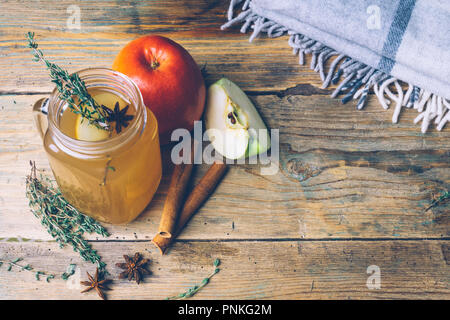 Apple cider (mulled apple cider) or chai-der with cinnamon sticks and fresh apples on wooden background. Autumn drinks. Winter mood. Copy space. Stock Photo