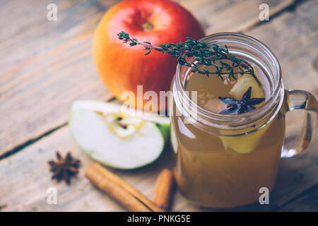 Apple cider (mulled apple cider) or chai-der with cinnamon sticks and fresh apples on wooden background. Autumn drinks. Winter mood. Stock Photo