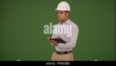 Latino architect contractor wearing hard hat with pad device on green screen Stock Photo