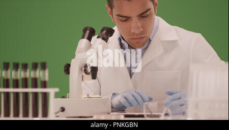 Millennial Hispanic medical scientist working in his lab on green screen Stock Photo