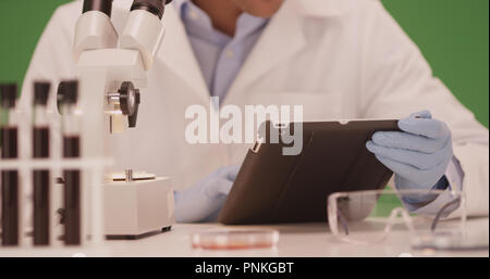 Millennial Latino medical scientist using tablet computer on green screen Stock Photo