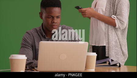 Millennials using phone and working on the computer on green screen Stock Photo