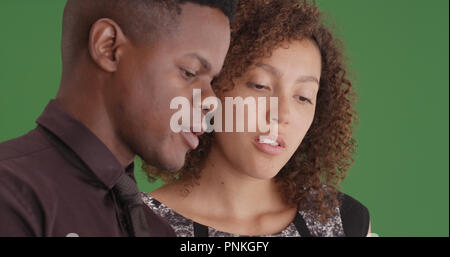 Close-up of two black millennial coworkers talking on green screen Stock Photo