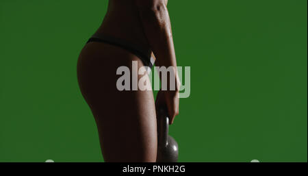 Side view of strong woman athlete doing kettle bell exercises on green screen Stock Photo