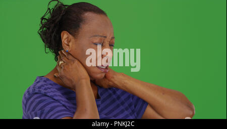 Mature black woman with bad neck pain on green screen Stock Photo