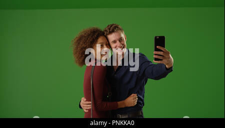 Happy dating couple using smartphone to take selfie on green screen Stock Photo