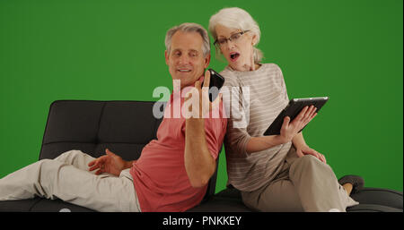 Mature husband showing wife something on phone on green screen Stock Photo