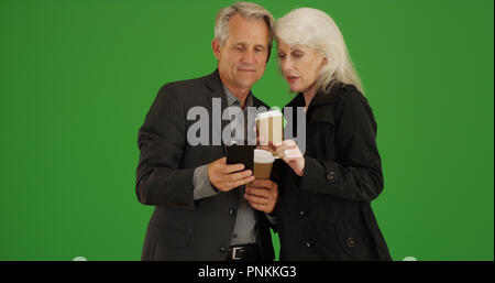 Modern senior couple using smartphone to get directions on green screen Stock Photo