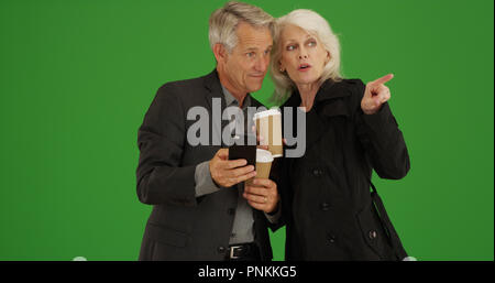 Modern seniors using smartphone to get directions on green screen Stock Photo