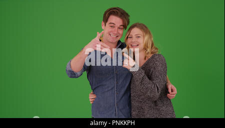 Happy excited homeowners showing off key to new home on green screen Stock Photo