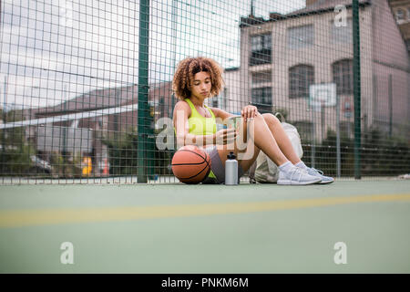 Young adult female on a basketball court using smartphone Stock Photo