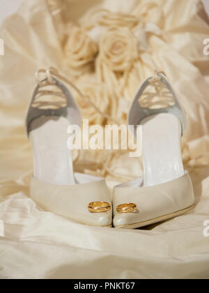 wedding rings and women's shoes with a dress on the background Stock Photo