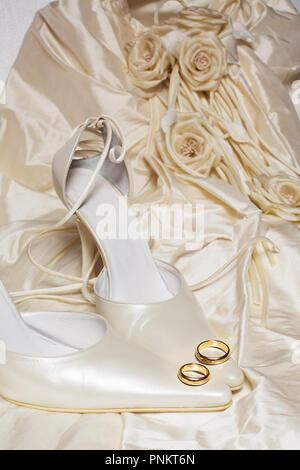 wedding rings and women's shoes with a dress on the background Stock Photo