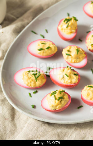 Homemade Pink Pickled Deviled Eggs with Chives Stock Photo