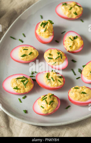 Homemade Pink Pickled Deviled Eggs with Chives Stock Photo